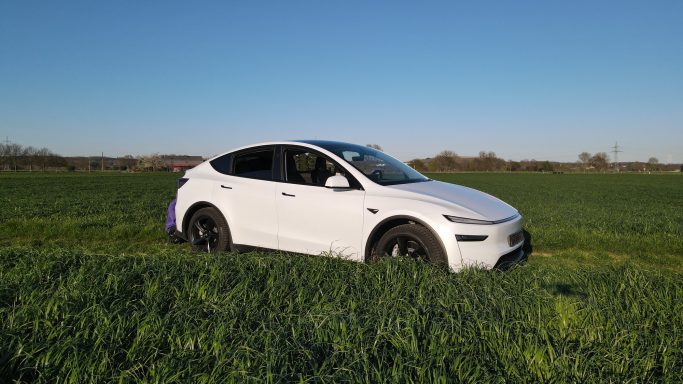Weißes SUV auf einer grünen Wiese unter klarem Himmel.